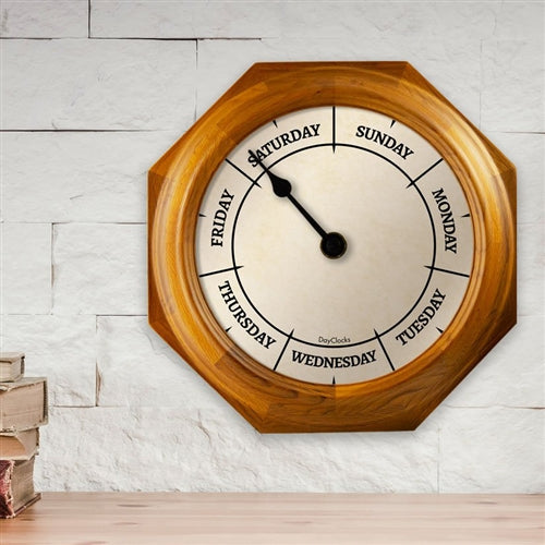 Wooden wall clock with days of the week on a white brick wall background