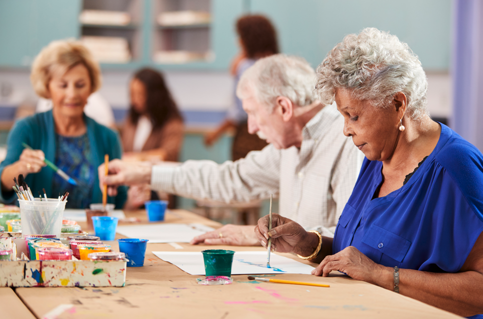 Group of elderly people engaged in an art activity at a table.