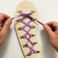 Person tying purple laces on a wooden shoe dexterity and hand eye coordination activity