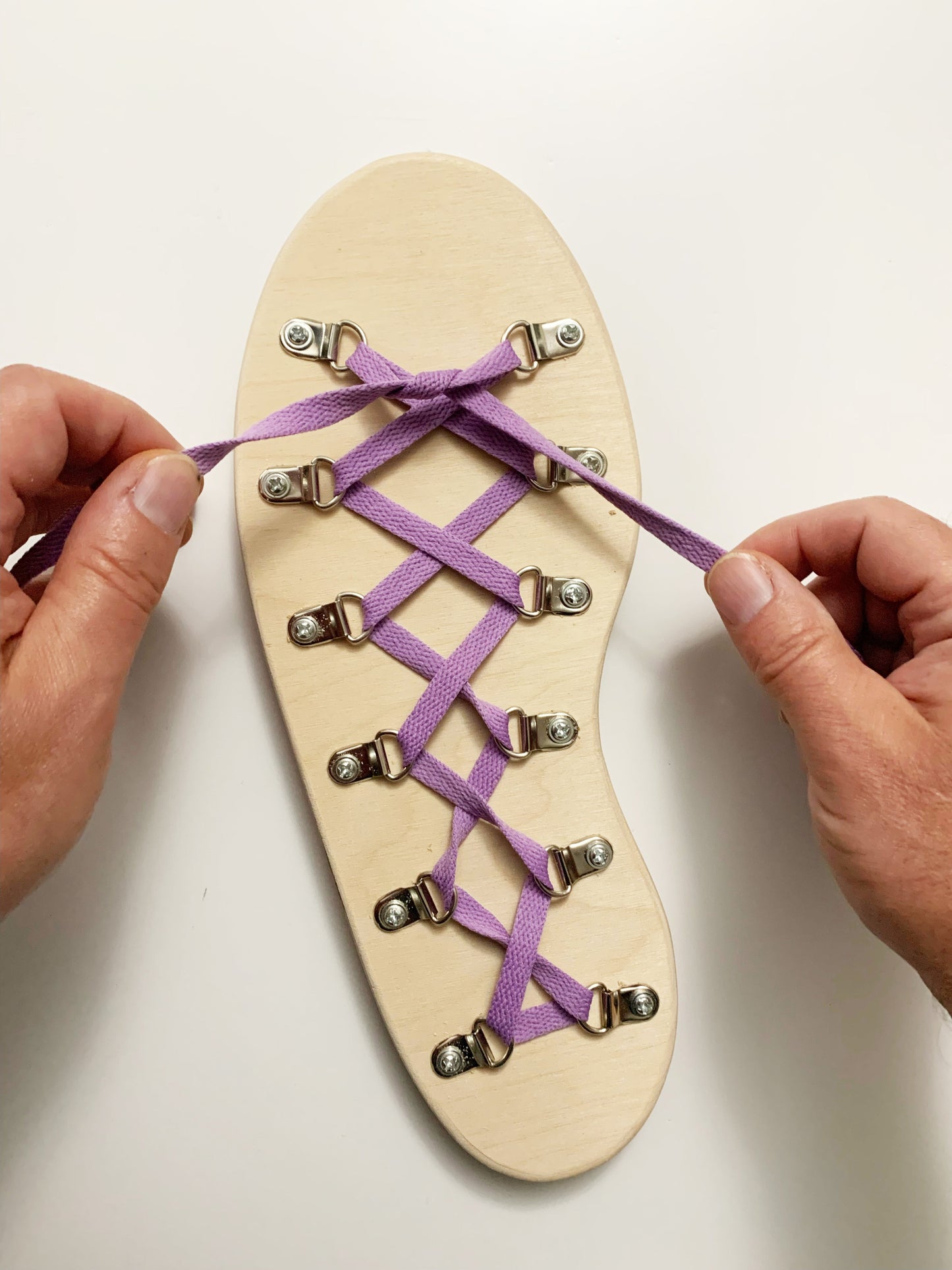 Person tying purple laces on a wooden shoe dexterity and hand eye coordination activity