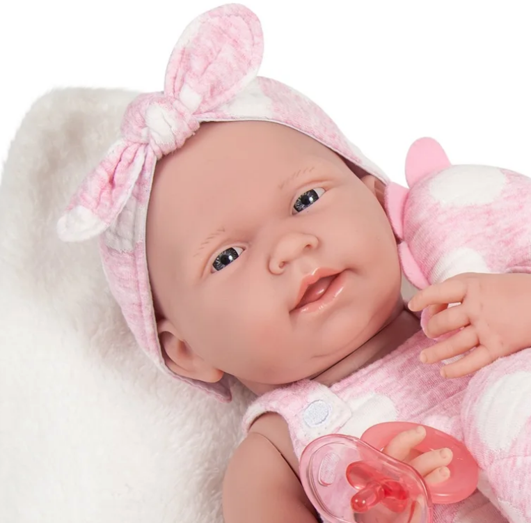 Baby doll wearing a pink outfit with a bow headband for dementia therapy