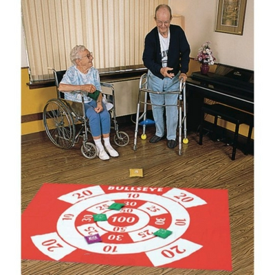 Two elderly individuals with a large target on the floor throwing bean bags to hit target