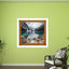 Framed nature print on a green wall with a chair and plants below.