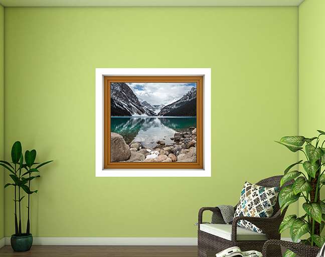 Framed nature print on a green wall with a chair and plants below.