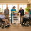 Caregiver in blue showing sunshine items  on cart to seniors in community room