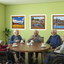 Seniors around table with coffee pointing at murals